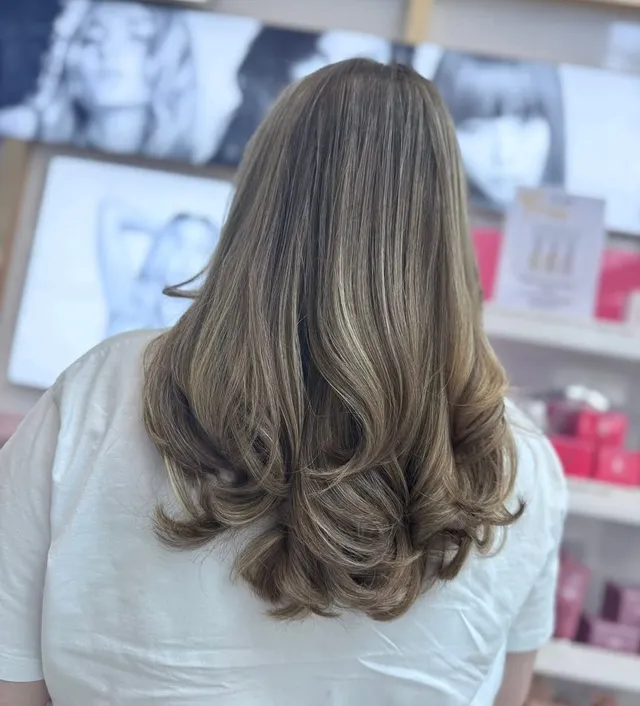 Dimensional caramel-blonde balayage with a bouncy blow-dry, by Room 97