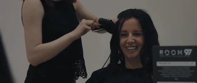 A happy client having her hair finished at Room 97